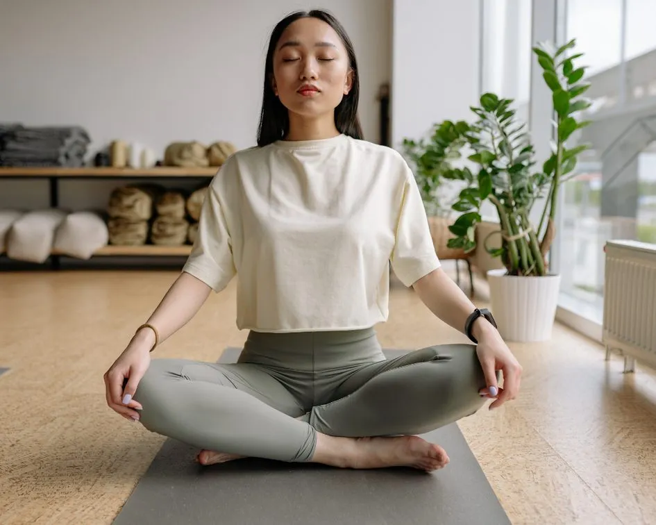 A woman meditating cross-legged in soft morning light
